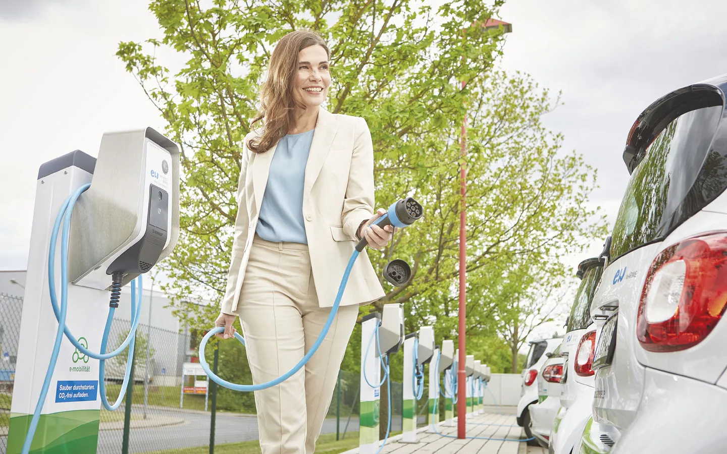 E-Mobilität - Kundin vor Ladestation mit Stecker in der Hand &middot; Palzer Elektro